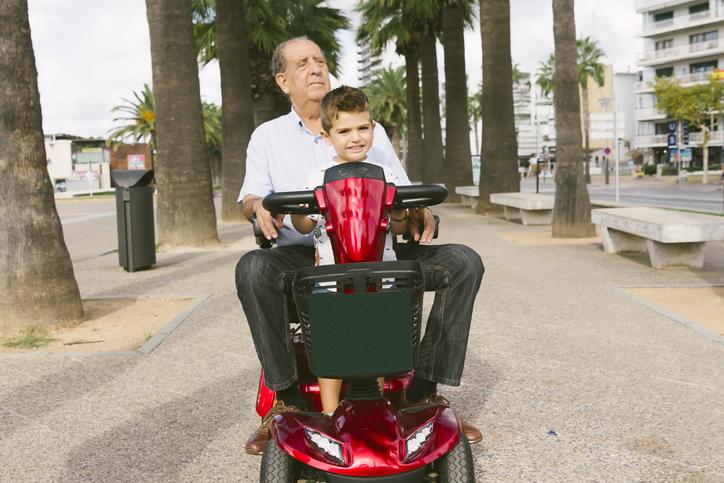 adulto mayor montado en scooter electrico con su nieto